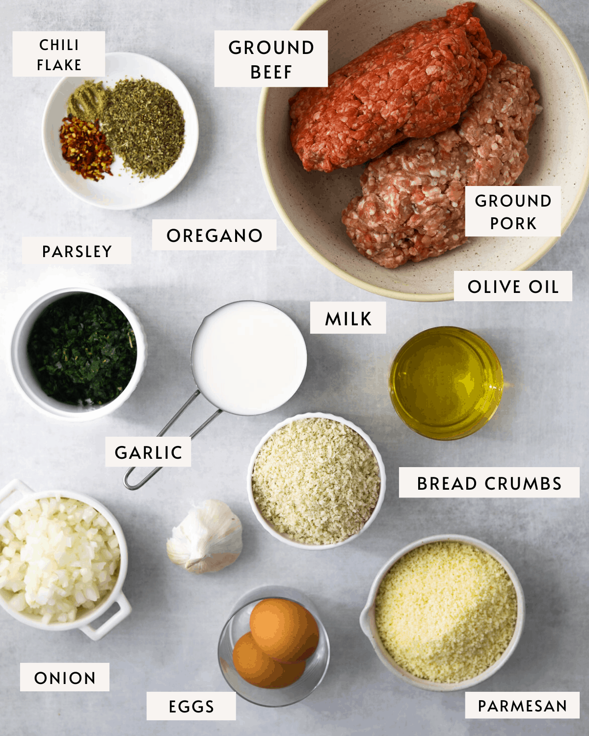 meatball ingredients in individual dishes prepped for cooking: ground beef, ground pork, breadcrumbs, spices, etc