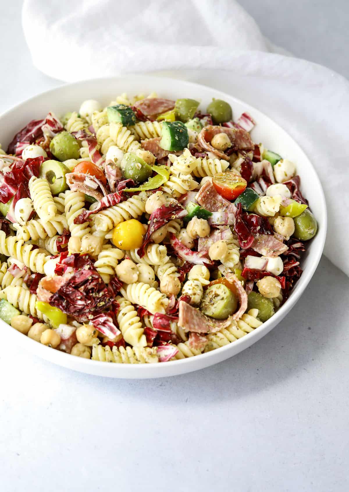 a white bowl filled with Italian Pasta Salad on a blue background