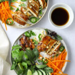 two bowls of Vietnamese rice noodle salad topped with basil, cilantro, mint and chicken