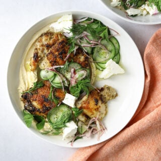 one bowl of za'atar grilled chicken with hummus and cucumber, red onion, feta and herbs