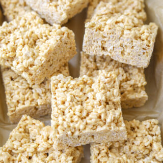 caramelized white chocolate rice crispy treats cut into squares stacked on top of one another.