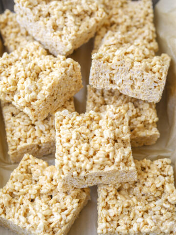 caramelized white chocolate rice crispy treats cut into squares stacked on top of one another.