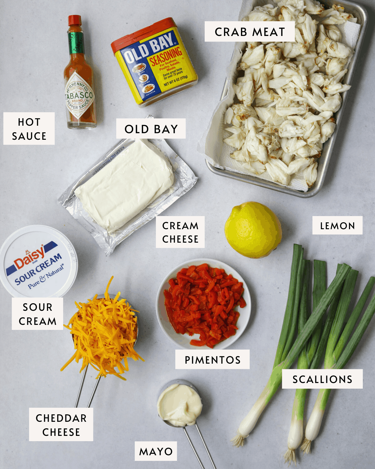 recipe ingredients on a blue background, crab meat, cheddar cheese, pimentos, scallions, cream cheese