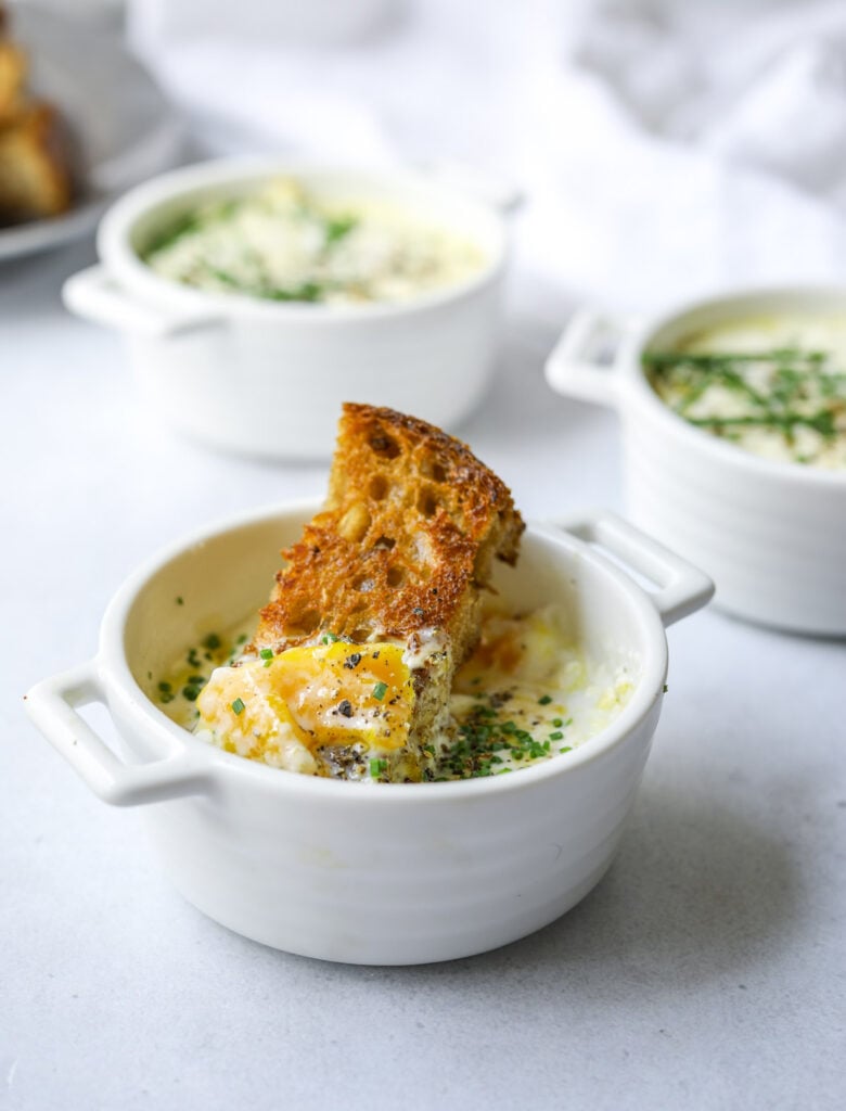 a close up of toasted bread dipping onto a baked eggs