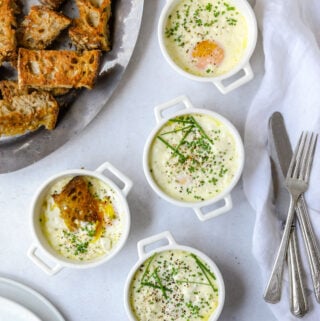 4 ramekins filled with creamy baked eggs topped with chives and black pepper