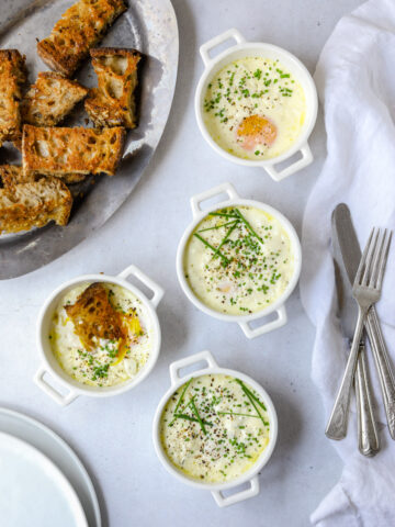 4 ramekins filled with creamy baked eggs topped with chives and black pepper