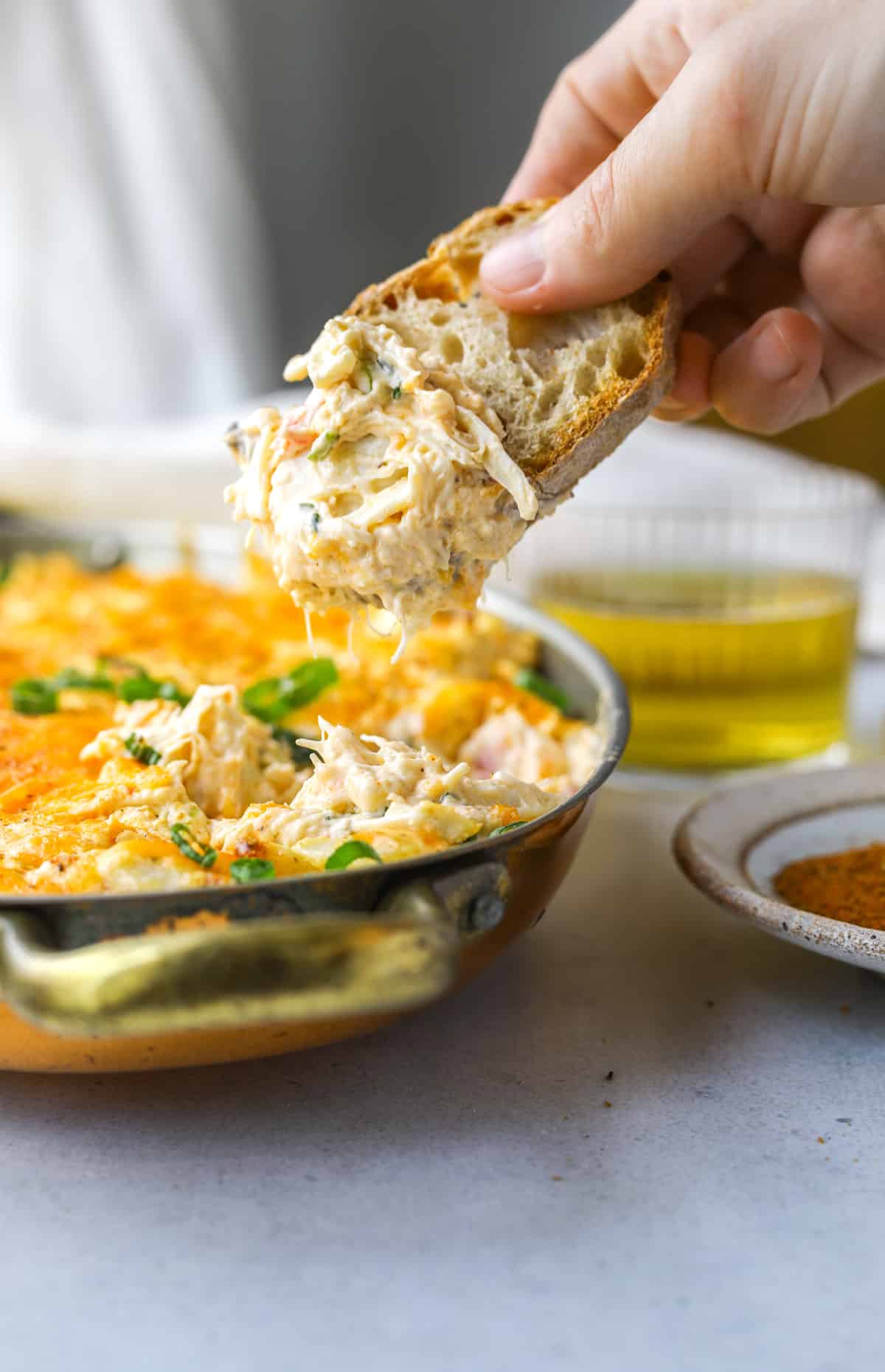 a piece of bread dipping into crab dip