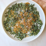 a white bowl filled with kale caesar salad with grated parmesan cheese