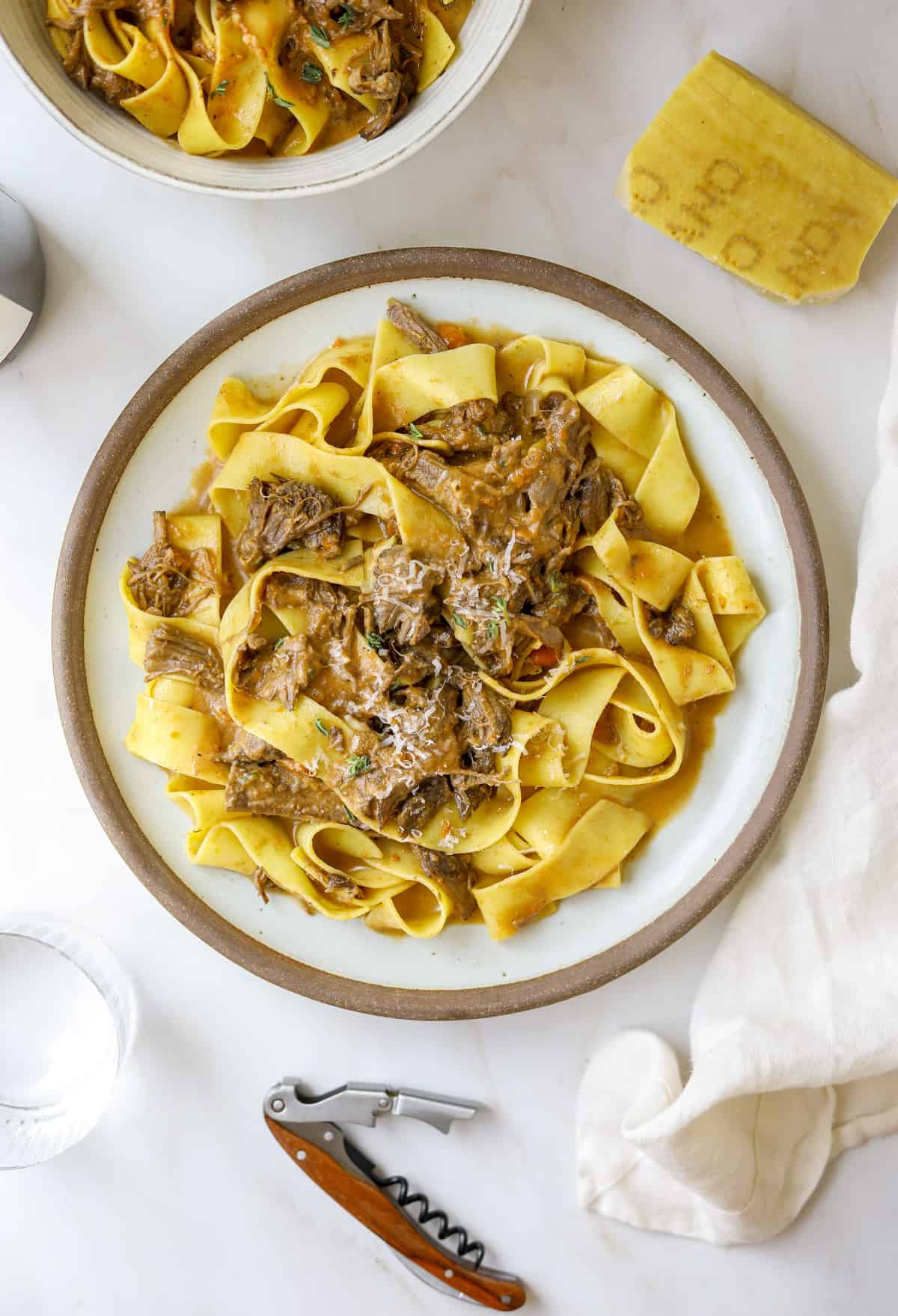 a plate of pasta with parmesan cheese and a glass of wine