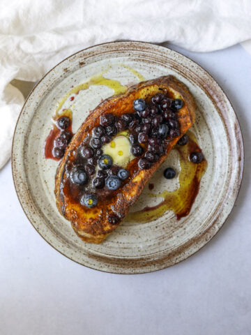 a slice of sourdough french toast topped with blueberry sauce and butter