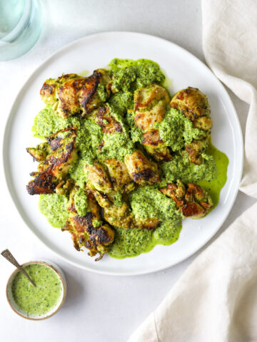 a white plate on a blue background with chicken and green sauce