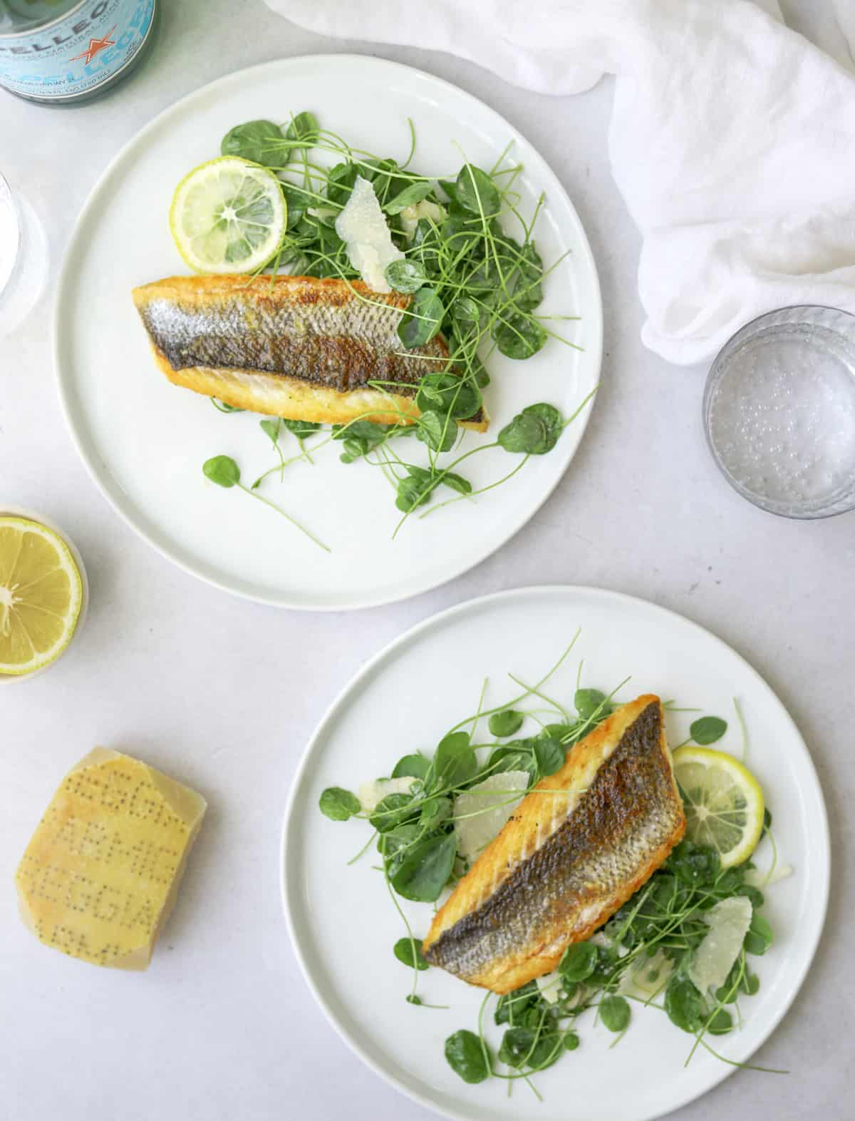 two white plates with branzino filets and watercress salad