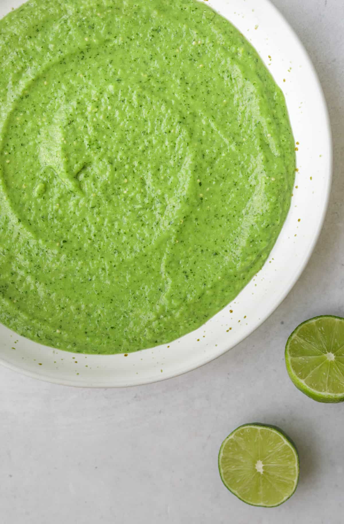 a close up picture of bright green creamy avocado salsa in white bowl