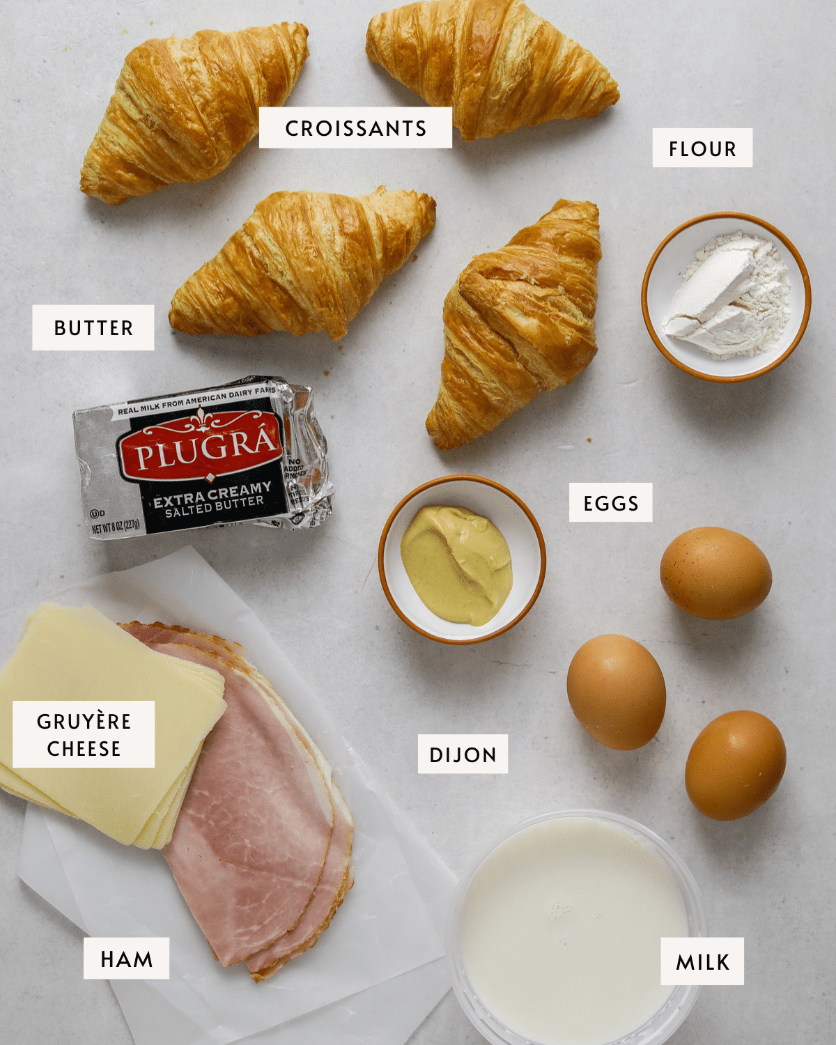 4 mini croissants, butter, a small white dish of flour, dijon mustard, three eggs, a cup of milk, sliced gruyère cheese and ham