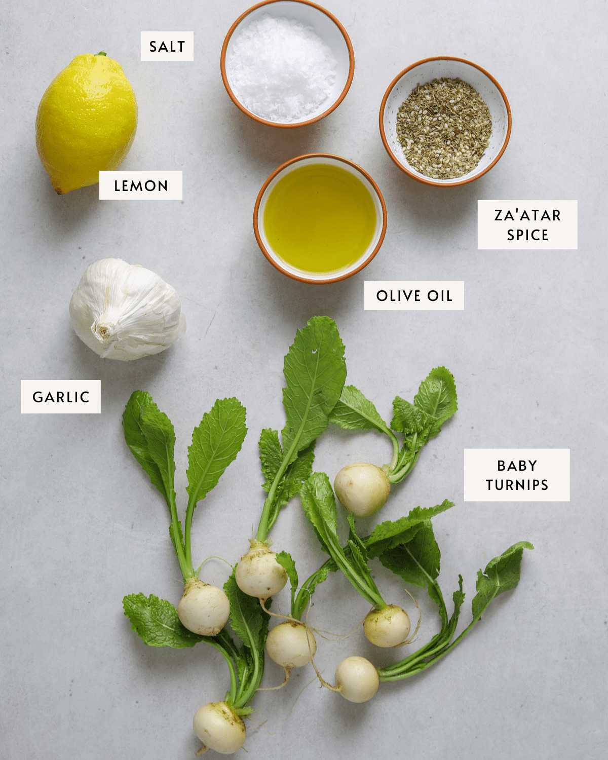 7 baby turnips, a bowl of olive oil, a lemon, a head of garlic, flakey sea salt and a white bowl of za'atar spice