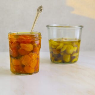 a mason jar filled with cherry tomato confit on a white background