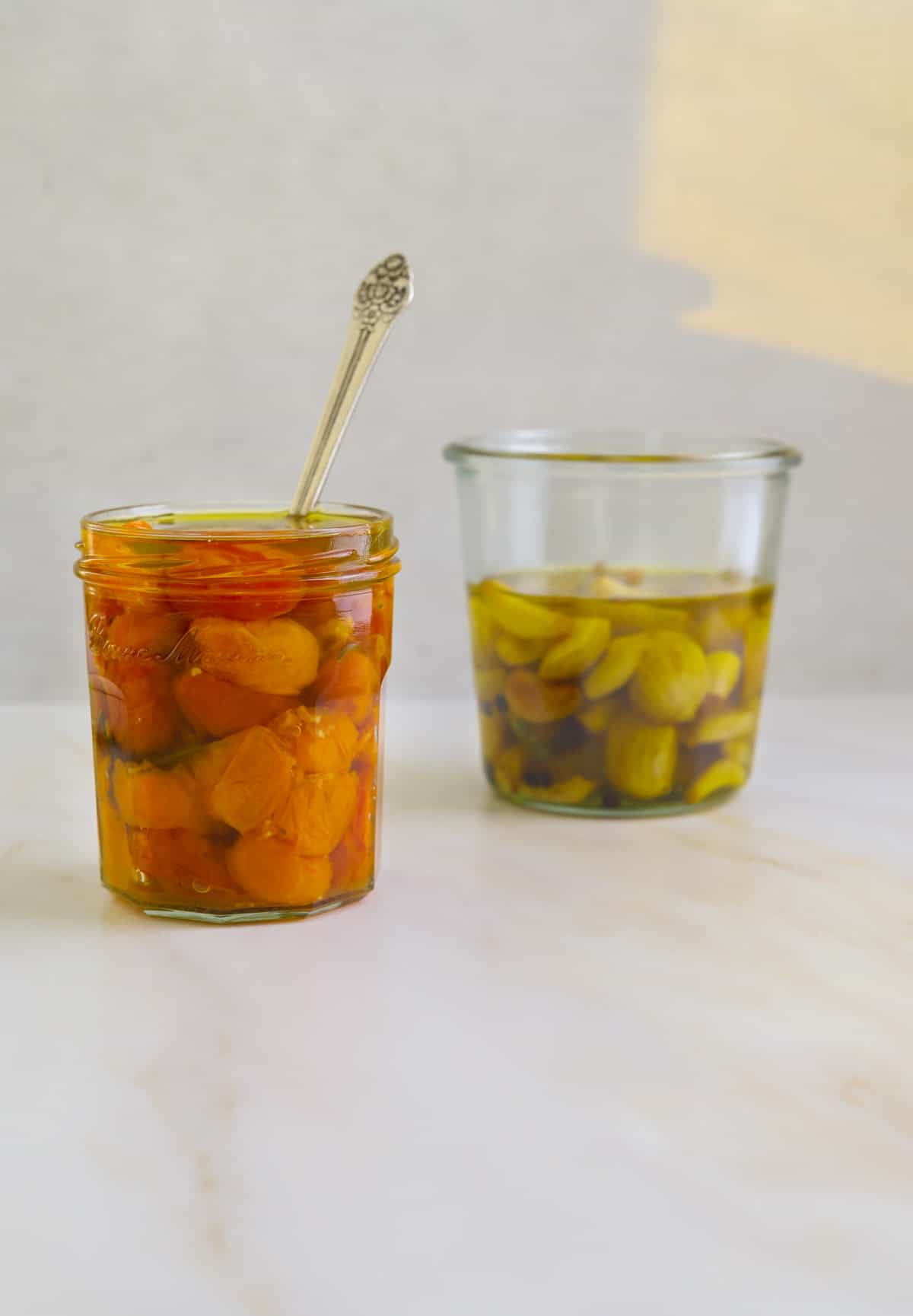 a mason jar filled with cherry tomato confit on a white background