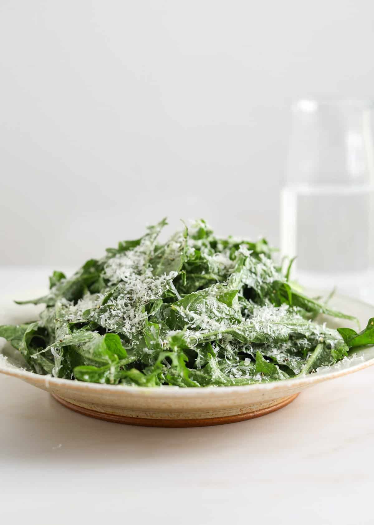 A heaping bowl of dandelion green salad topped with grated pecorino cheese.