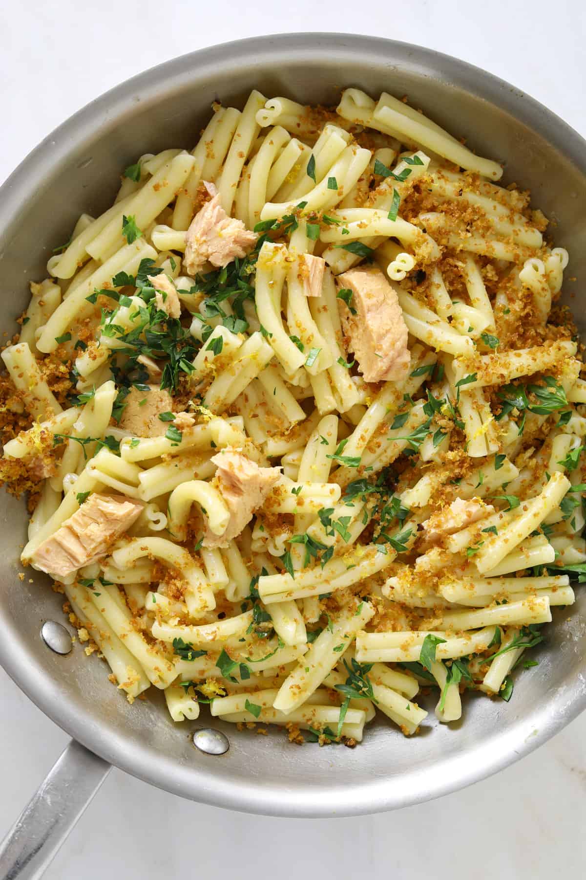 pasta in a saute pan with chunks of tuna, chopped parsley and breadcrumbs
