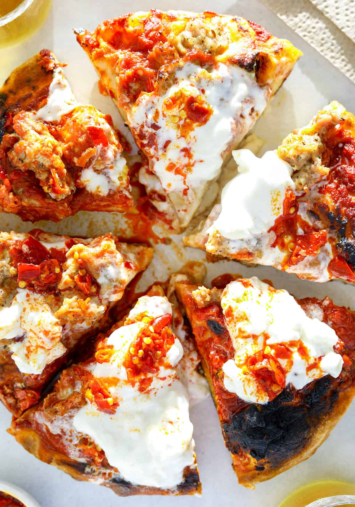 a pizza cut into 6 slices topped with burrata cheese and hot chilis