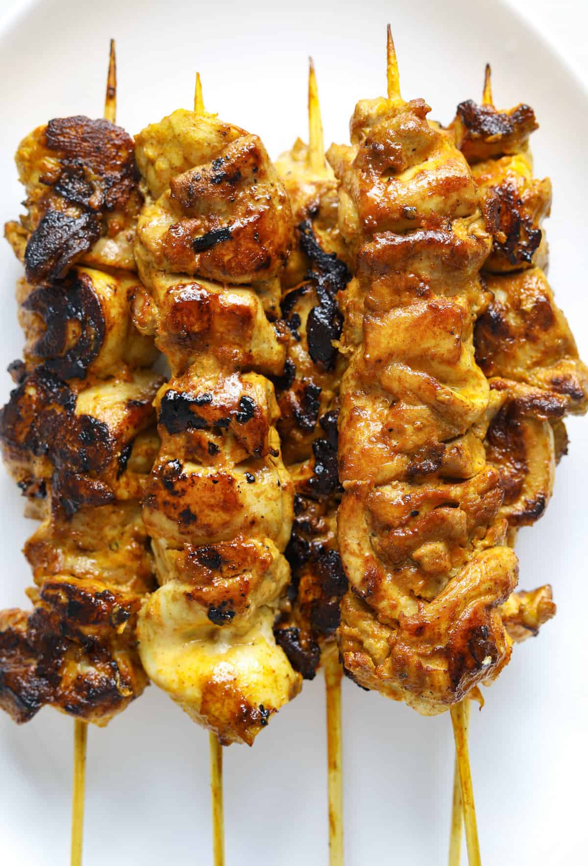 a close up image of charred chicken kebabs.