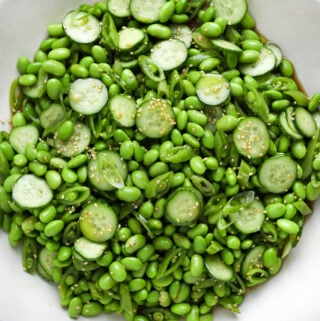 a white ceramic serving bowl filled with edamame salad.