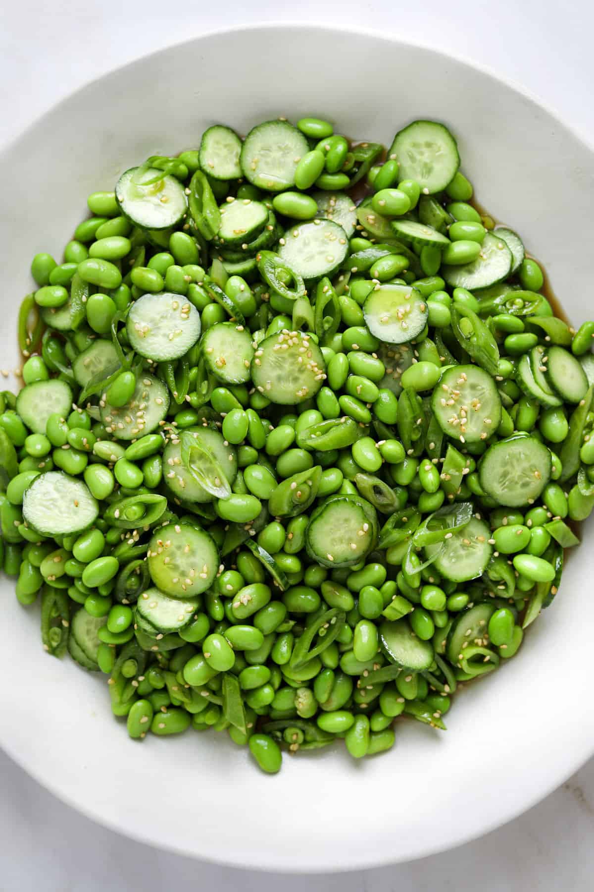 a white ceramic serving bowl filled with edamame salad.