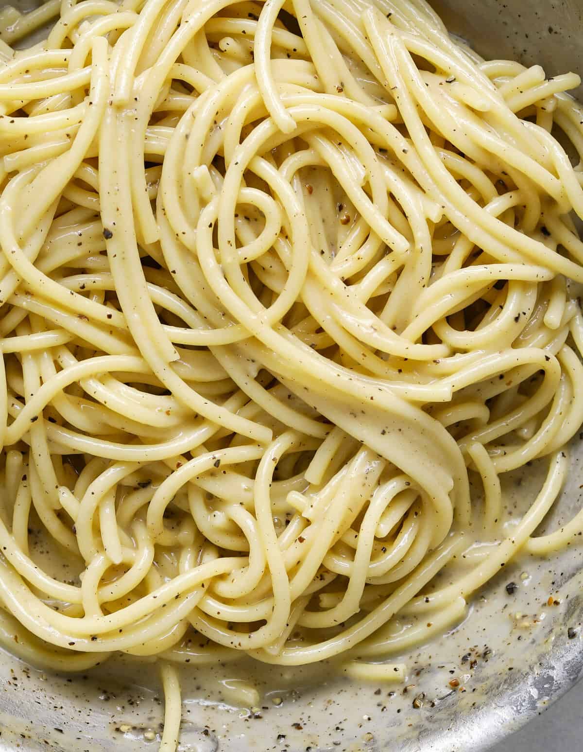 A close up image of pasta with black pepper in a sauce pan.