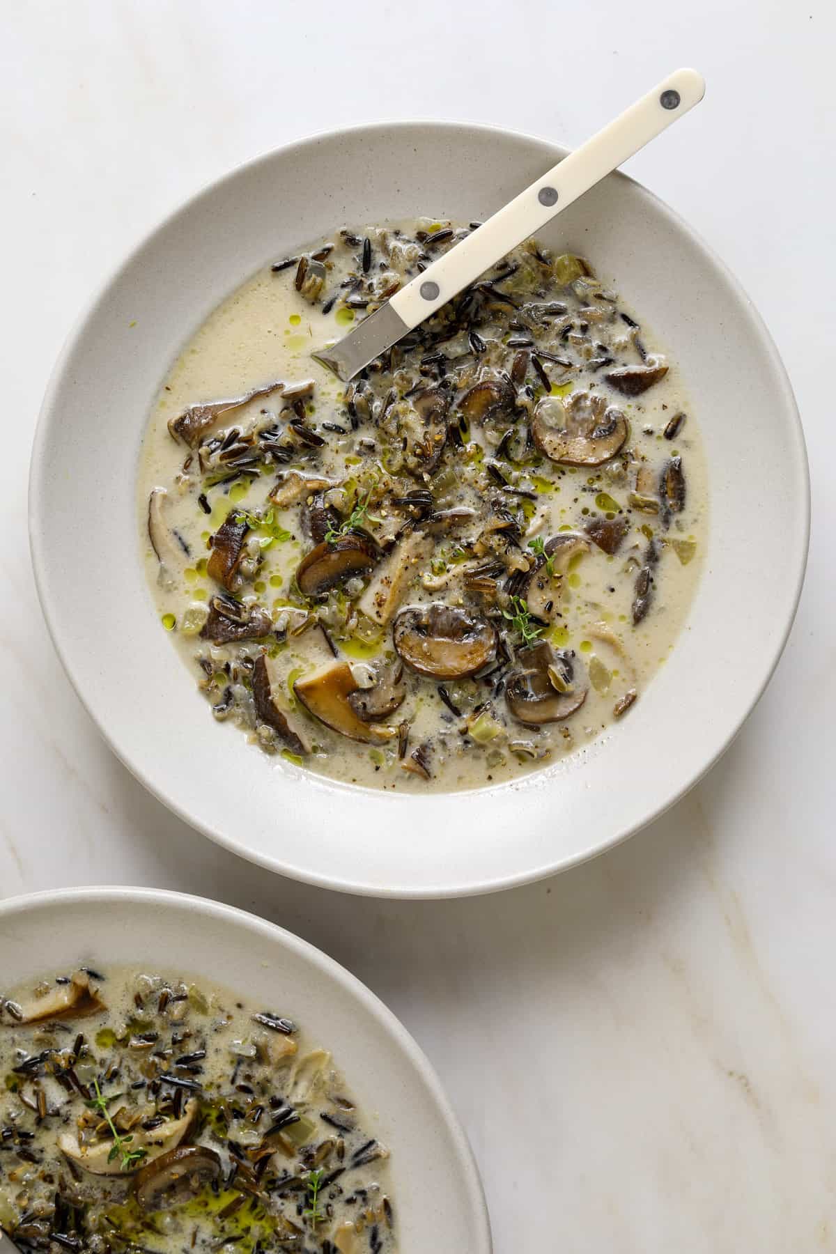 A spoon dipping into a bowl of wild rice soup.