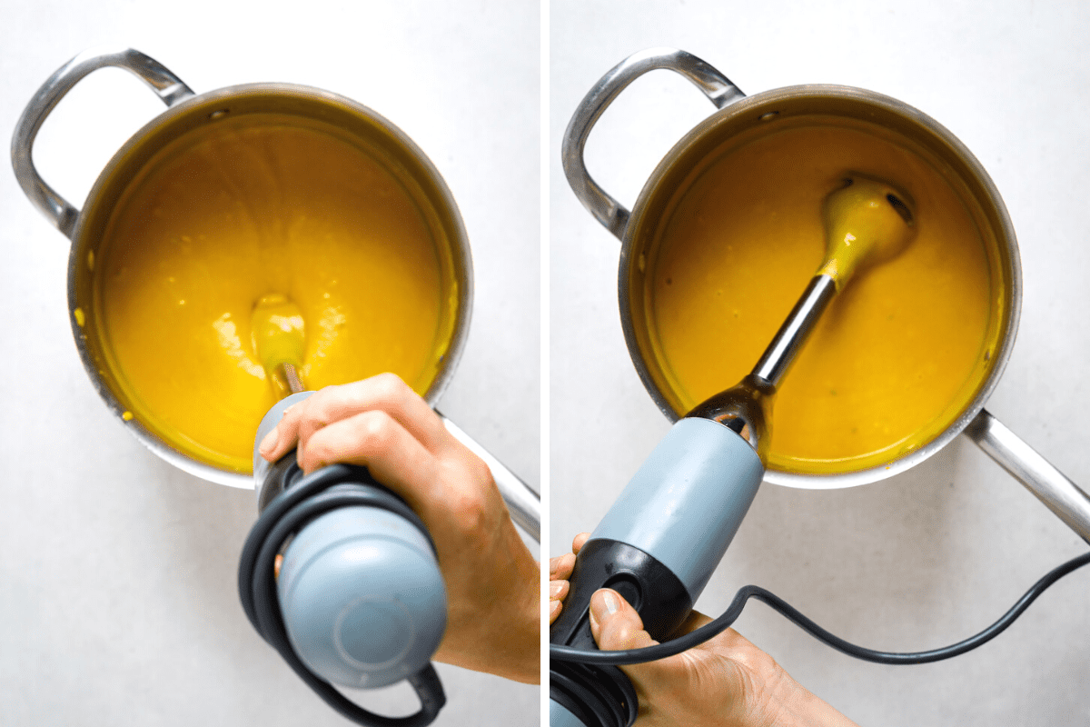 Two stainless steel pots filled with soup being blended with a hand blender.