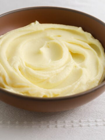 A bowl of potato purée on a white tablecloth.