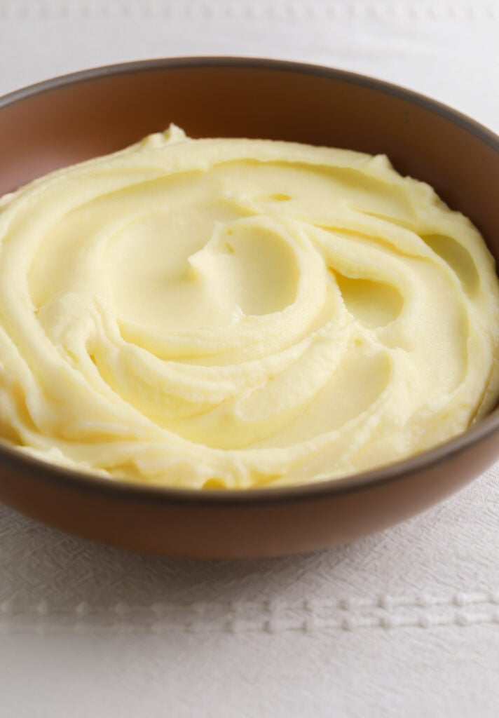 A bowl of potato purée on a white tablecloth.