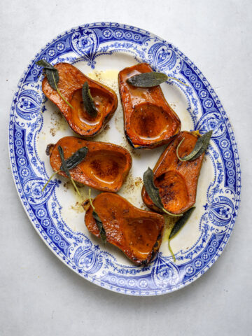 Roasted squash on a platter with sage and butter.