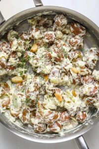 Creamy, smashed potatoes with sour cream and whole garlic cloves in a pot.