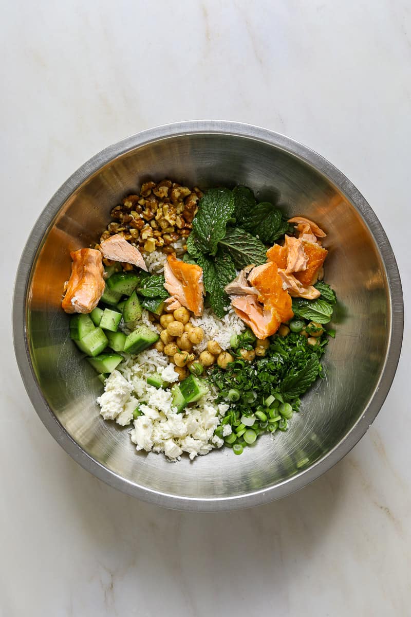 A stainless steel mixing bowl filled with salad ingredients.