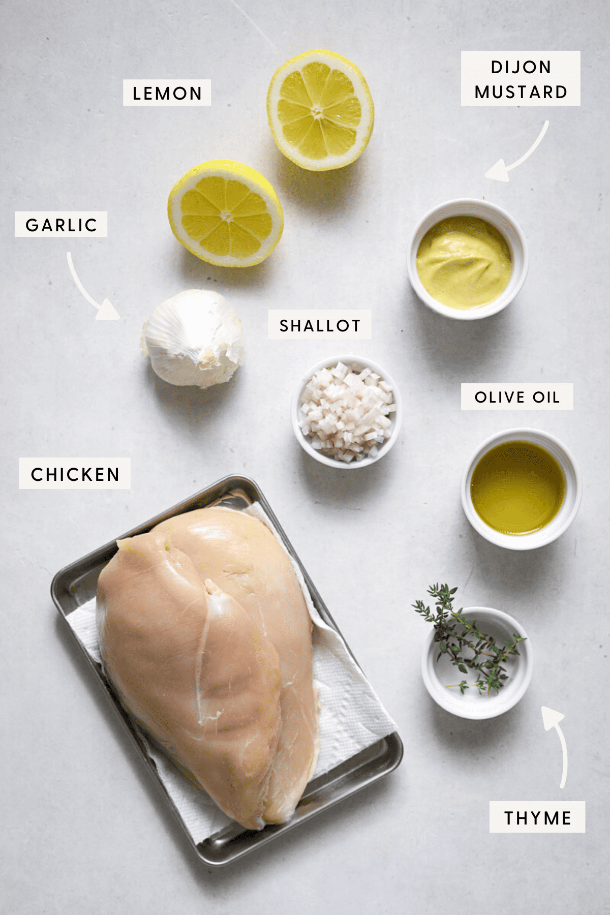 Recipe ingredients individually portioned and labled; one lemon, dijon mustard, minced shallot, olive oil, chicken breast, fresh thyme and a garlic bulb.