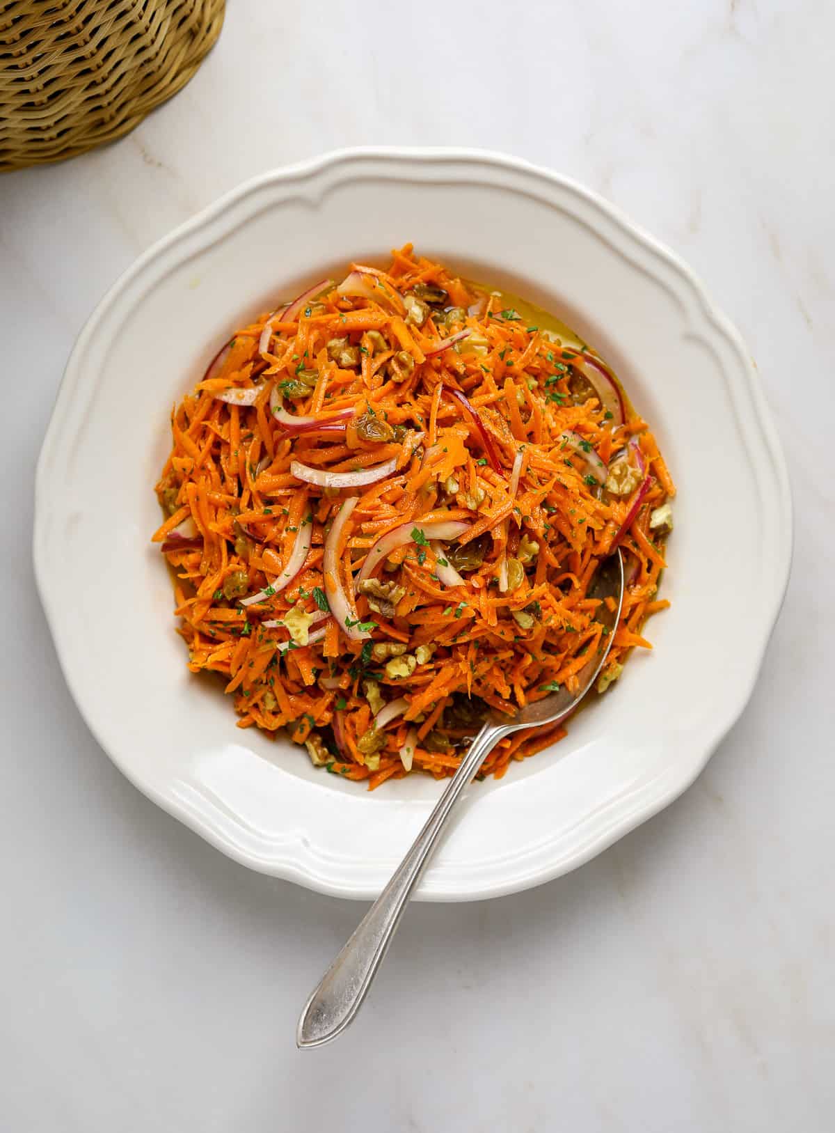 Grated Carrot Salad in a white bowl on a marble table.