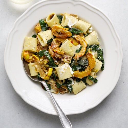 A bowl of pasta with roasted squash and kale.