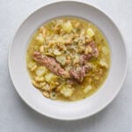 A bowl of soup with beans, meat and cabbage.