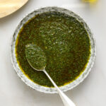 Chimichurri sauce in a bowl with a silver spoon.