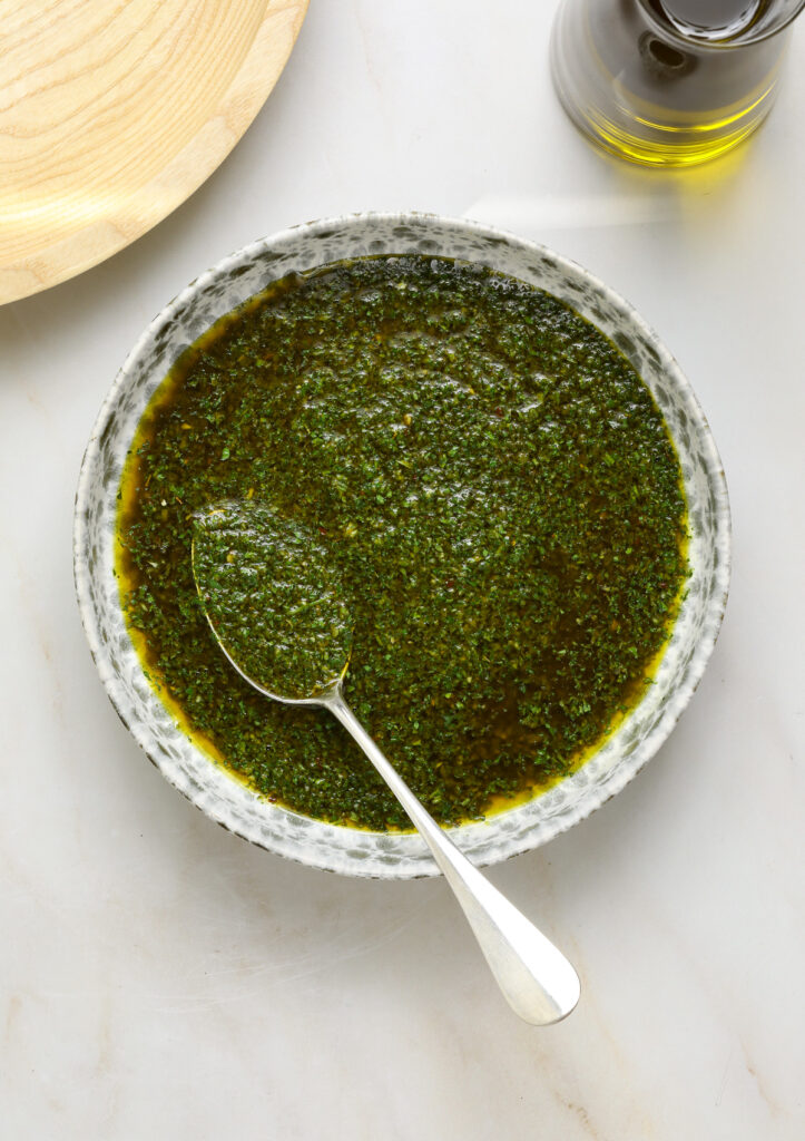 Chimichurri sauce in a bowl with a silver spoon.