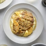 A bowl filled with a pork chop, apple and whole grain mustard sauce.