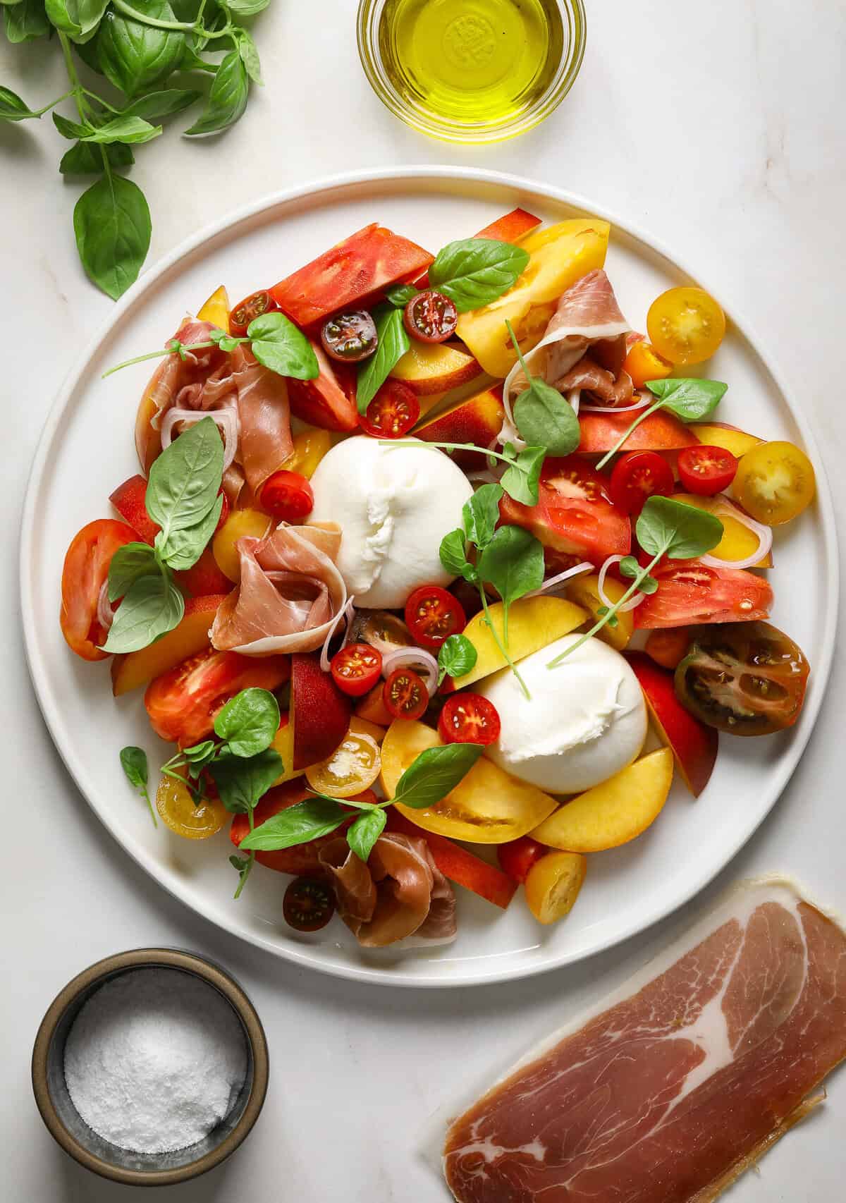 A large white platter filled with a vibrant summer salad.