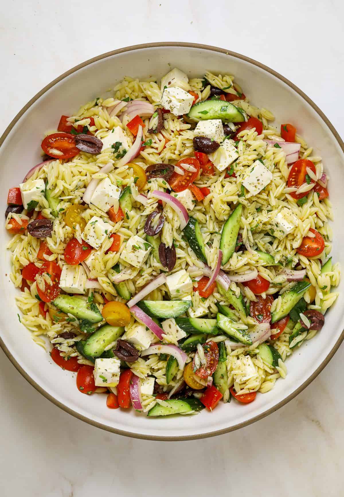 A large, white ceramic bowl filled with orzo salad.