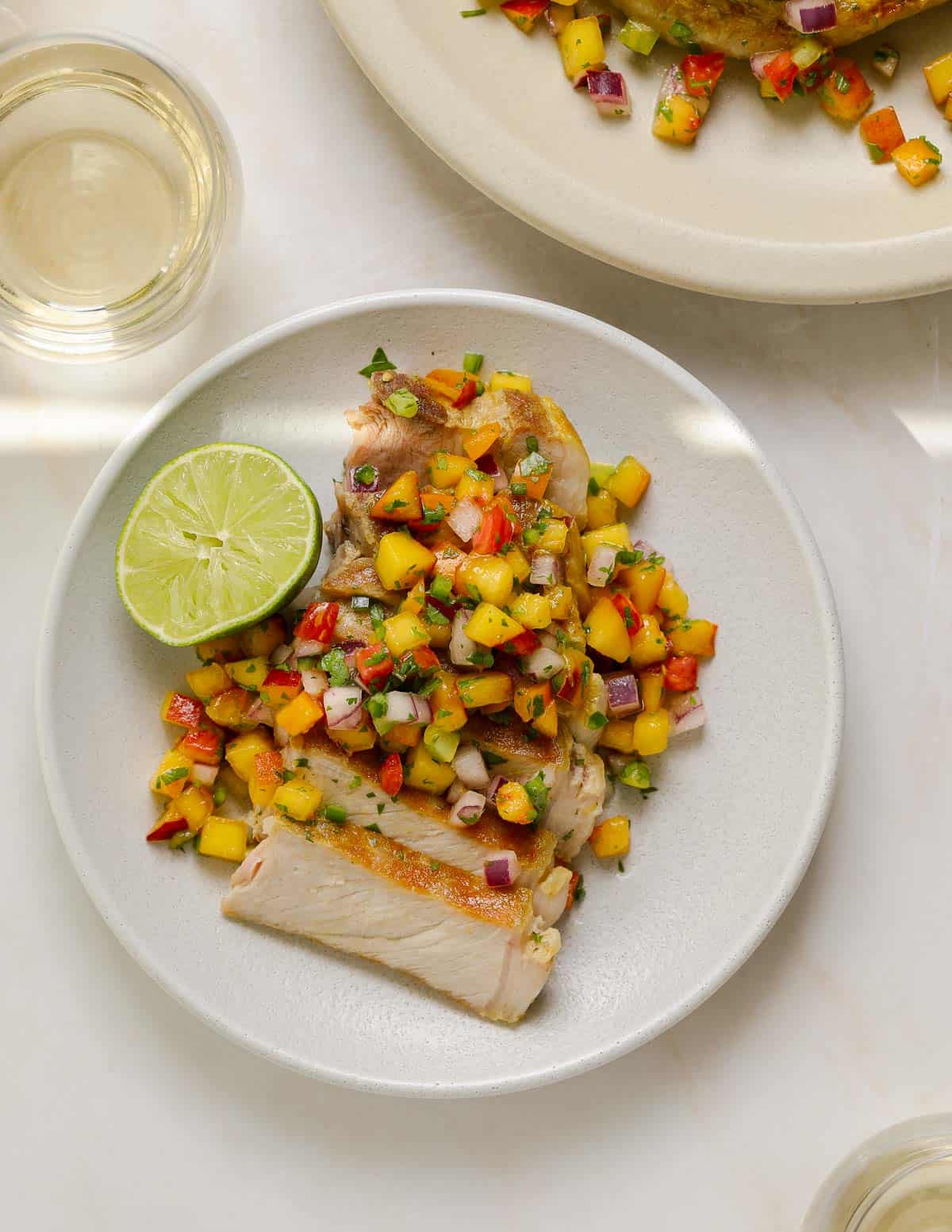 A sliced pork chop topped with peach salsa.