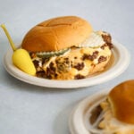 A cheese burger on a paper plate.