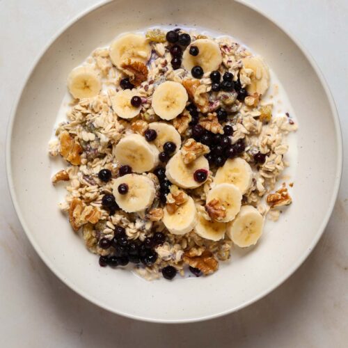 A bowl of oats, sliced banana, blue berries and walnuts.