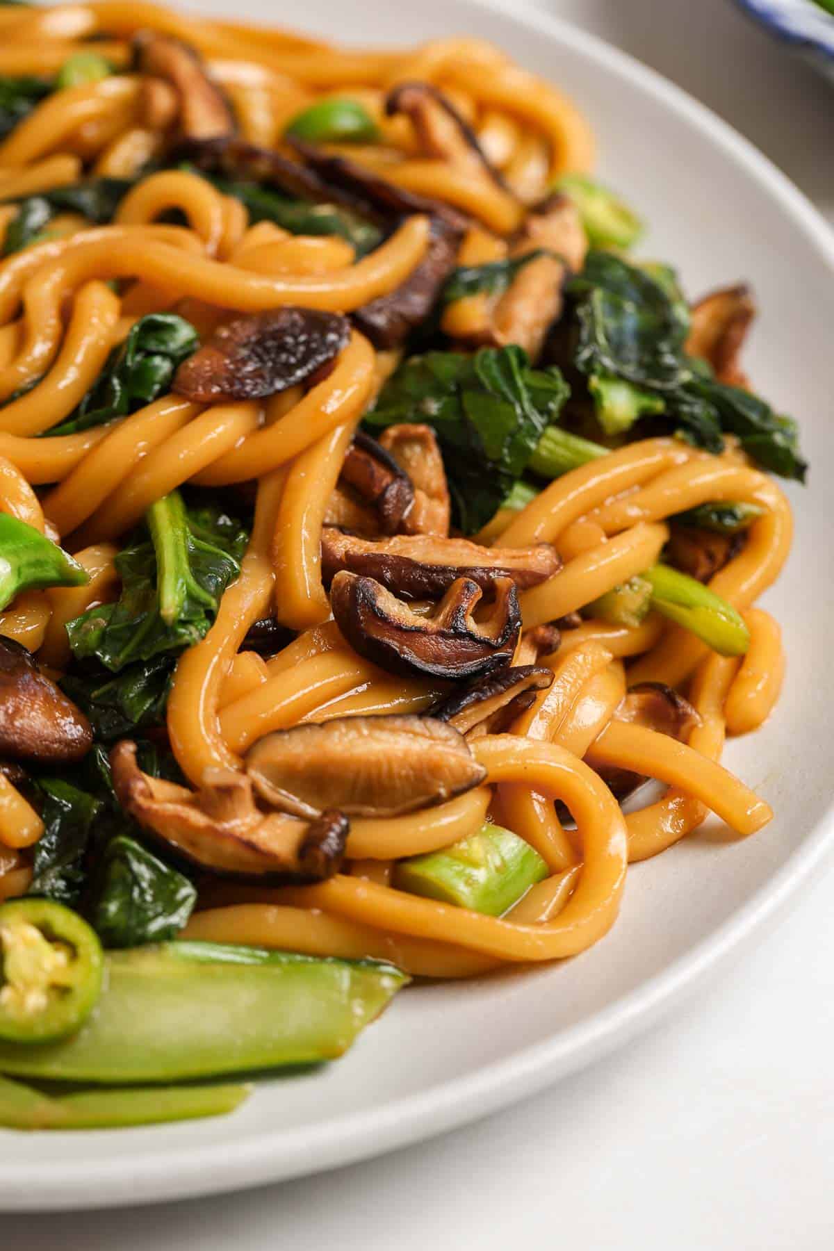 A close up image of stir fried udon noodles on a plate.