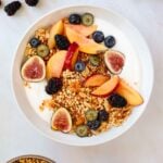 A bowl of granola and yogurt surrounded by a small dish of honey and a jar of yogurt.