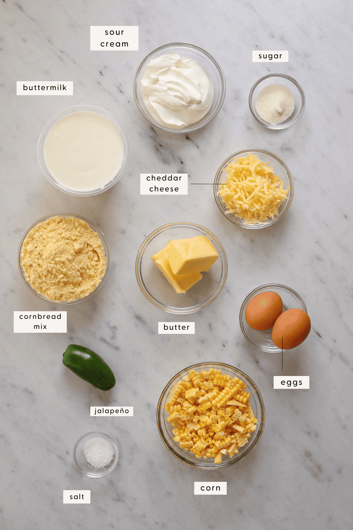 Recipe ingredients portioned into individual bowls on a marble tabletop.